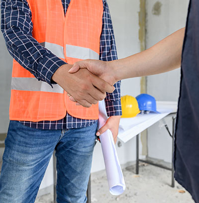 Asian Engineer and architect handshake at construction property site. Teamwork and Successful housing estate building project